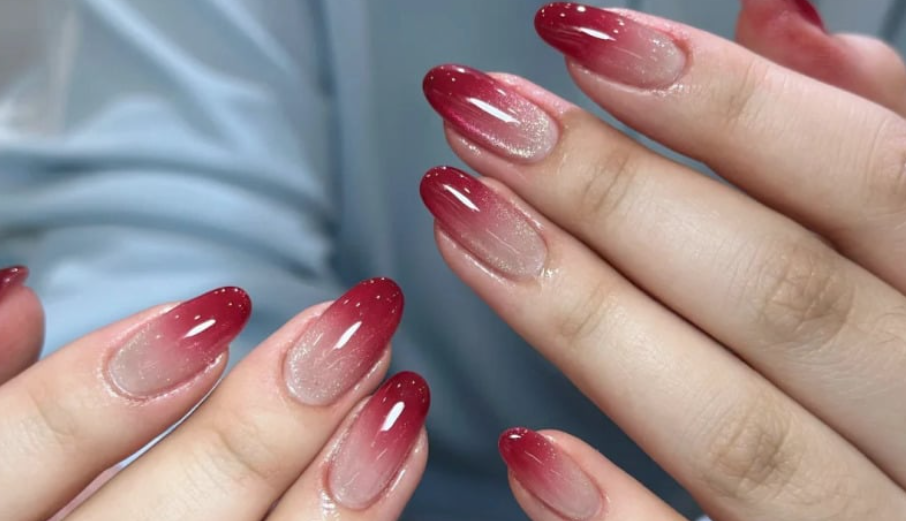 TOP 20+ Mẫu Nail Đỏ Trắng Đẹp Mê Mẩn Cho Nàng Thêm Xinh 2 Bàn tay với móng tay ombre đỏ, dài và bóng, trên nền áo màu xanh nhạt.