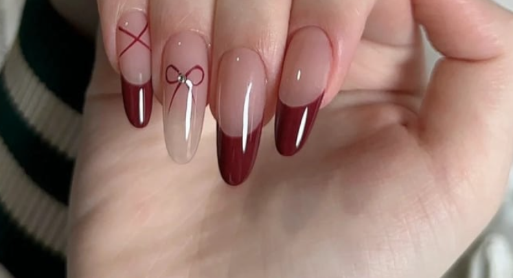 TOP 20+ Mẫu Nail Đỏ Trắng Đẹp Mê Mẩn Cho Nàng Thêm Xinh 3 Bàn tay với móng tay dài, sơn màu đỏ và họa tiết nơ, chụp từ góc nhìn gần.