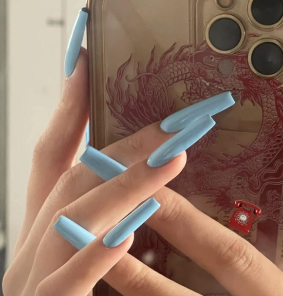 Tổng Hợp Mẫu Nail Màu Xanh Dương Nhạt Đẹp Nhẹ Nhàng Hot Nhất 2025 5 Bàn tay với móng dài màu xanh dương cầm điện thoại có ốp lưng in hình rồng đỏ.