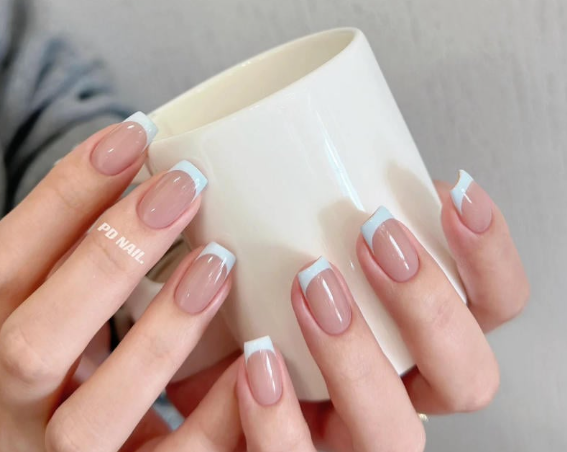 Tổng Hợp Mẫu Nail Màu Xanh Dương Nhạt Đẹp Nhẹ Nhàng Hot Nhất 2025 7 Hai bàn tay với móng tay sơn kiểu Pháp cầm một chiếc cốc trắng.