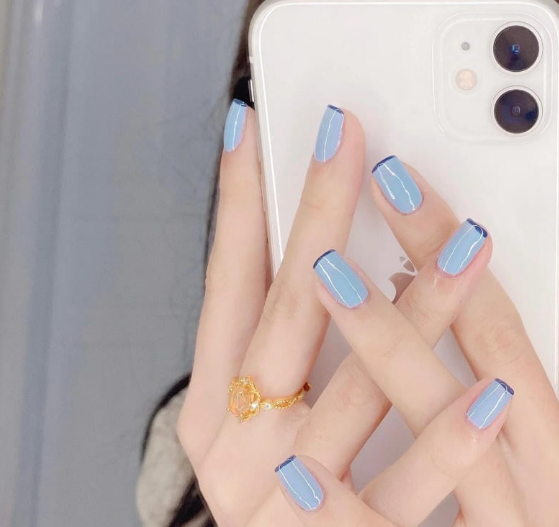 Tổng Hợp Mẫu Nail Màu Xanh Dương Nhạt Đẹp Nhẹ Nhàng Hot Nhất 2025 8 Tay với móng sơn màu xanh cầm điện thoại, đeo nhẫn vàng.