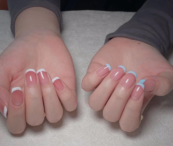 Tổng Hợp Mẫu Nail Màu Xanh Dương Nhạt Đẹp Nhẹ Nhàng Hot Nhất 2025 10 Hai bàn tay với móng tay được sơn kiểu Pháp, đầu móng màu trắng và xanh, đặt trên bề mặt vải trắng.