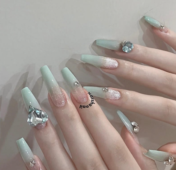 Tổng Hợp Mẫu Nail Màu Xanh Dương Nhạt Đẹp Nhẹ Nhàng Hot Nhất 2025 15 Bộ móng tay dài màu xanh nhạt, trang trí đá lấp lánh và kim tuyến lấp lánh, trên nền da sáng.