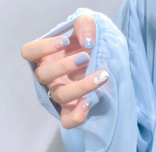 Tổng Hợp Mẫu Nail Màu Xanh Dương Nhạt Đẹp Nhẹ Nhàng Hot Nhất 2025 23 Bàn tay với móng tay được sơn màu xanh nhạt và họa tiết dễ thương, mặc áo màu xanh nhạt.