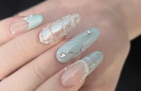 Tổng Hợp Mẫu Nail Màu Xanh Dương Nhạt Đẹp Nhẹ Nhàng Hot Nhất 2025 29 Bàn tay với móng tay được trang trí công phu, sử dụng màu xanh nhạt, ngọc trai và họa tiết kim loại lấp lánh.