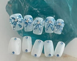 Tổng Hợp Mẫu Nail Màu Xanh Dương Nhạt Đẹp Nhẹ Nhàng Hot Nhất 2025 30 Bộ móng giả màu xanh da trời và trắng được trang trí với họa tiết nơ và đá lấp lánh.
