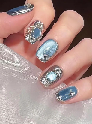 Tổng Hợp Mẫu Nail Màu Xanh Dương Nhạt Đẹp Nhẹ Nhàng Hot Nhất 2025 31 Bàn tay với móng tay được sơn màu xanh và bạc, trang trí họa tiết kim loại nổi bật.