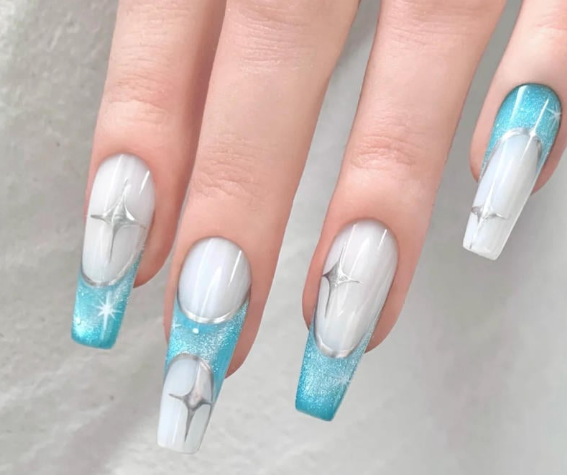 Tổng Hợp Mẫu Nail Màu Xanh Dương Nhạt Đẹp Nhẹ Nhàng Hot Nhất 2025 35 Bàn tay với móng tay dài, thiết kế màu xanh và trắng, có họa tiết ngôi sao lấp lánh trên nền sáng.