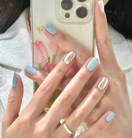 Tổng Hợp Mẫu Nail Màu Xanh Dương Nhạt Đẹp Nhẹ Nhàng Hot Nhất 2025 43 Người cầm điện thoại có móng tay sơn màu xanh và bạc, nền điện thoại in hình hoa tulip.