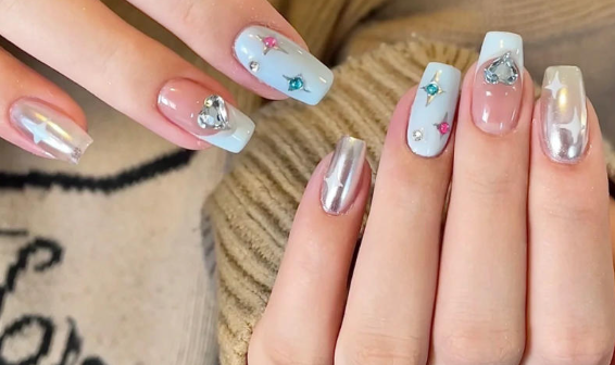 Tổng Hợp Mẫu Nail Màu Xanh Dương Nhạt Đẹp Nhẹ Nhàng Hot Nhất 2025 46 Bàn tay với móng tay được sơn màu xanh nhạt và trang trí bằng đá lấp lánh, nổi bật trên nền áo len màu be.