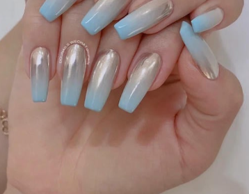 Tổng Hợp Mẫu Nail Màu Xanh Dương Nhạt Đẹp Nhẹ Nhàng Hot Nhất 2025 47 Bàn tay với móng tay dài được sơn màu xanh và bạc bóng, cầm nhẹ một vật thể không rõ trên nền trắng.