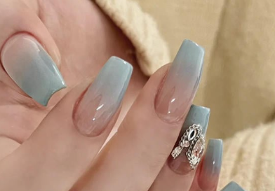 Tổng Hợp Mẫu Nail Màu Xanh Dương Nhạt Đẹp Nhẹ Nhàng Hot Nhất 2025 50 Bàn tay với móng tay dài sơn ombre màu xanh, có đính đá trang trí trên một móng.