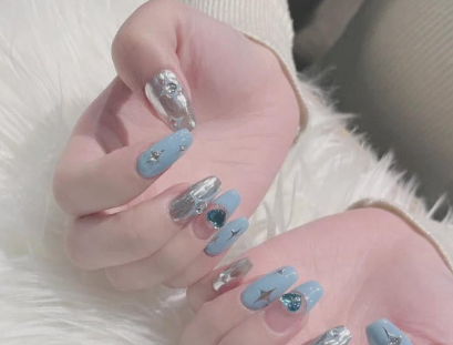 Tổng Hợp Mẫu Nail Màu Xanh Dương Nhạt Đẹp Nhẹ Nhàng Hot Nhất 2025 51 Hai bàn tay với móng tay dài được sơn màu xanh và bạc, trang trí họa tiết ánh kim và hình ngôi sao.