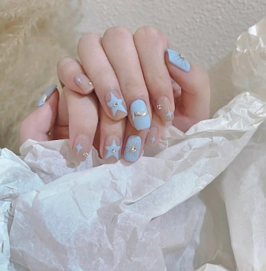 Tổng Hợp Mẫu Nail Màu Xanh Dương Nhạt Đẹp Nhẹ Nhàng Hot Nhất 2025 60 Bàn tay với móng tay được sơn màu xanh nhạt và trang trí hình ngôi sao cùng trăng lưỡi liềm.