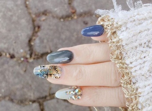 Tổng Hợp Mẫu Nail Màu Xanh Dương Nhạt Đẹp Nhẹ Nhàng Hot Nhất 2025 69 Bàn tay với móng tay được sơn màu sắc đa dạng và trang trí họa tiết, nền là mặt đường lát gạch.
