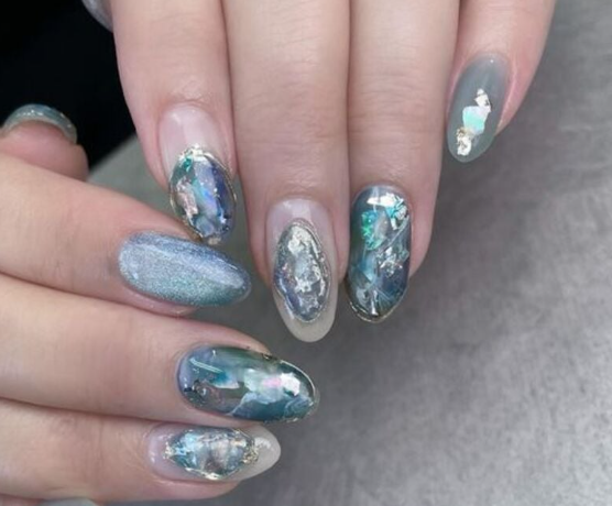 Tổng Hợp Mẫu Nail Màu Xanh Dương Nhạt Đẹp Nhẹ Nhàng Hot Nhất 2025 70 Bàn tay với móng tay được trang trí nghệ thuật màu xanh và bạc, thiết kế ánh kim và họa tiết trừu tượng.