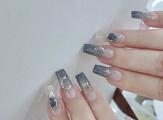 Tổng Hợp Mẫu Nail Màu Xanh Dương Nhạt Đẹp Nhẹ Nhàng Hot Nhất 2025 74 Bàn tay với móng tay dài, trang trí họa tiết và màu sắc gradient xanh xám nhạt, có điểm nhấn ánh kim.