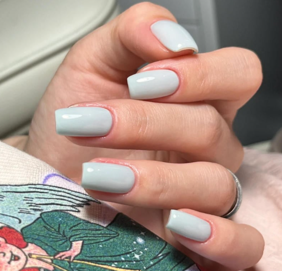Tổng Hợp Mẫu Nail Màu Xanh Dương Nhạt Đẹp Nhẹ Nhàng Hot Nhất 2025 76 Bàn tay với móng tay sơn màu xanh nhạt, cầm một tấm vải có họa tiết màu sắc.