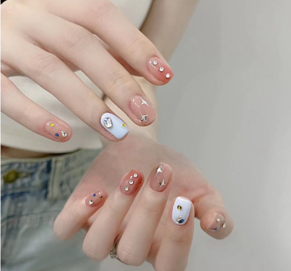 99+ mẫu nail đính đá vừa XINH vừa SANG cho nàng tự tin ra ngoài 4 Bàn tay với móng tay được trang trí màu sắc và đính đá, nền màu trắng và hồng nhạt.