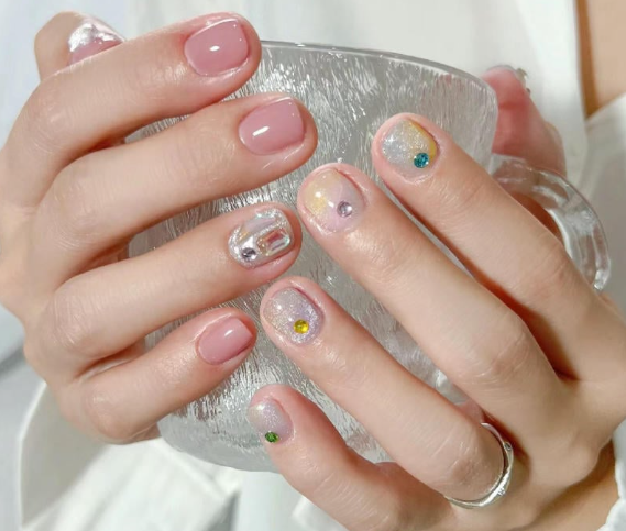 99+ mẫu nail đính đá vừa XINH vừa SANG cho nàng tự tin ra ngoài 5 Đôi tay với móng tay được sơn màu hồng nhạt và đính đá, cầm một chiếc cốc thủy tinh trong suốt.