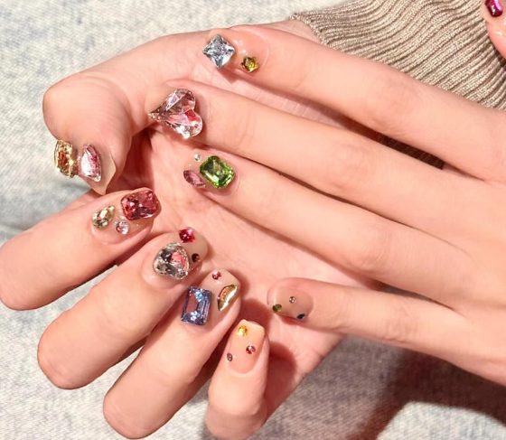 99+ mẫu nail đính đá vừa XINH vừa SANG cho nàng tự tin ra ngoài 7 Bàn tay với móng tay trang trí đá quý nhiều màu sắc, ánh sáng phản chiếu tạo hiệu ứng lấp lánh.