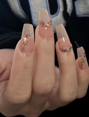 99+ mẫu nail đính đá vừa XINH vừa SANG cho nàng tự tin ra ngoài 10 Bàn tay với móng dài, được trang trí với đá quý nhiều màu sắc, trên nền màu sơn bóng màu nude.