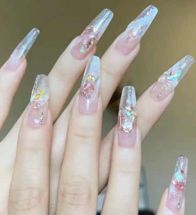 99+ mẫu nail đính đá vừa XINH vừa SANG cho nàng tự tin ra ngoài 17 Bàn tay với móng tay dài, thiết kế trong suốt và trang trí bằng đá và ánh kim lấp lánh.