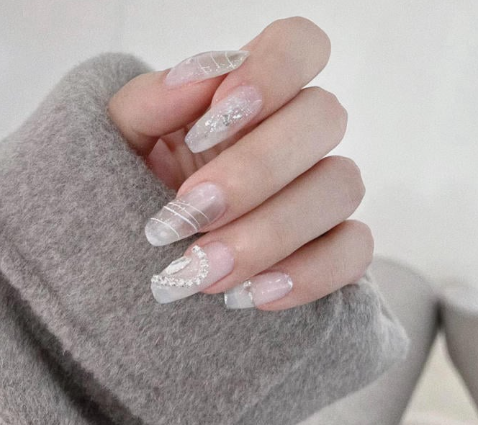 99+ mẫu nail đính đá vừa XINH vừa SANG cho nàng tự tin ra ngoài 29 Người cầm tay với móng tay dài, được trang trí họa tiết lấp lánh, nền màu xám nhạt.