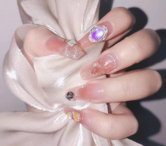99+ mẫu nail đính đá vừa XINH vừa SANG cho nàng tự tin ra ngoài 30 Bàn tay với móng tay được trang trí bằng sơn và đính đá, cầm một dải vải lụa màu kem lấp lánh.