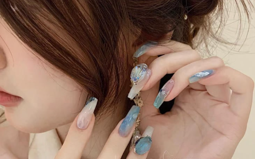 99+ mẫu nail đính đá vừa XINH vừa SANG cho nàng tự tin ra ngoài 31 Người phụ nữ với móng tay dài được trang trí nghệ thuật, tóc búi và đeo bông tai.
