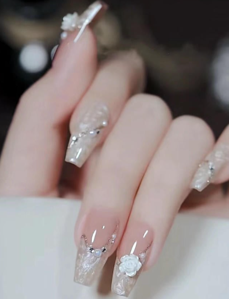 99+ mẫu nail đính đá vừa XINH vừa SANG cho nàng tự tin ra ngoài 34 Bàn tay với móng tay dài, trang trí hoa và đá lấp lánh trên nền màu trong suốt.