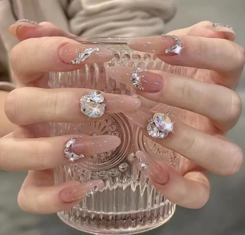 99+ mẫu nail đính đá vừa XINH vừa SANG cho nàng tự tin ra ngoài 36 Bàn tay với móng tay dài đính đá lấp lánh, cầm ly thủy tinh trong suốt với hoa văn tinh xảo.