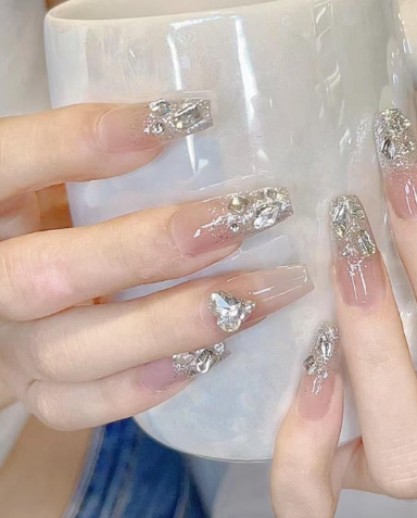 99+ mẫu nail đính đá vừa XINH vừa SANG cho nàng tự tin ra ngoài 49 Bàn tay đang cầm cốc trắng, móng tay được trang trí với họa tiết lấp lánh và đá quý.