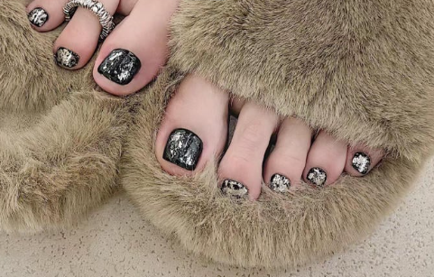 99+ mẫu nail đính đá vừa XINH vừa SANG cho nàng tự tin ra ngoài 65 Bàn chân với móng chân sơn màu đen họa tiết, mang dép lông màu nâu nhạt, trên nền sàn sáng màu.