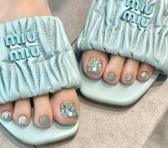 99+ mẫu nail đính đá vừa XINH vừa SANG cho nàng tự tin ra ngoài 67 Ngón chân sơn màu xanh và lấp lánh, mang dép màu xanh nhạt có họa tiết chữ nổi.