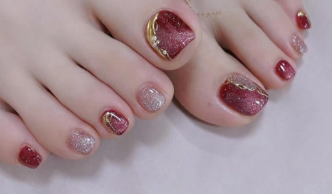 99+ mẫu nail đính đá vừa XINH vừa SANG cho nàng tự tin ra ngoài 68 Móng chân được sơn màu đỏ và bạc lấp lánh, có họa tiết trang trí vàng, trên nền phông màu nhạt.