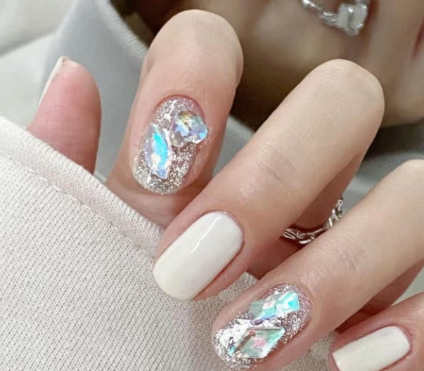 100+ Mẫu Nail Nhũ Đẹp Lấp Lánh Giúp Phái Nữ Tỏa Sáng Thời Thượng 1 Bàn tay với móng tay được sơn màu trắng và trang trí bằng họa tiết lấp lánh, ánh xà cừ.