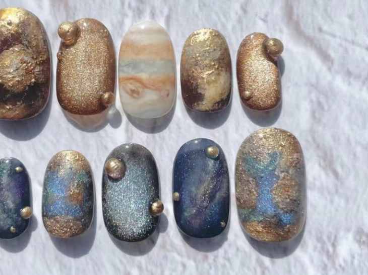 100+ Mẫu Nail Nhũ Đẹp Lấp Lánh Giúp Phái Nữ Tỏa Sáng Thời Thượng 2 Bộ móng tay được trang trí với các hoạ tiết màu sắc khác nhau, bao gồm ánh kim và vân đá, trên nền màu sáng.