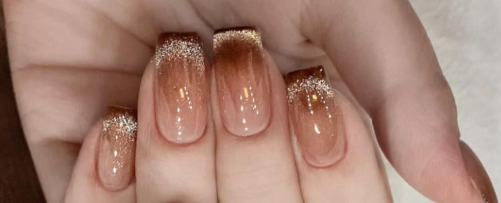 100+ Mẫu Nail Nhũ Đẹp Lấp Lánh Giúp Phái Nữ Tỏa Sáng Thời Thượng 4 Bàn tay với móng được sơn màu nâu ombre và điểm nhấn kim tuyến lấp lánh ở đầu móng.