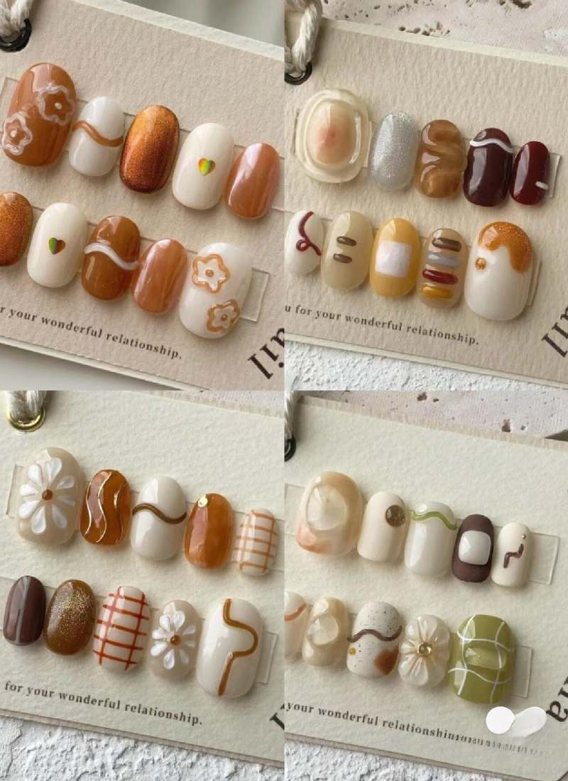 Bộ móng tay giả với nhiều kiểu trang trí đa dạng, bao gồm hoa, đường kẻ và họa tiết màu sắc khác nhau.