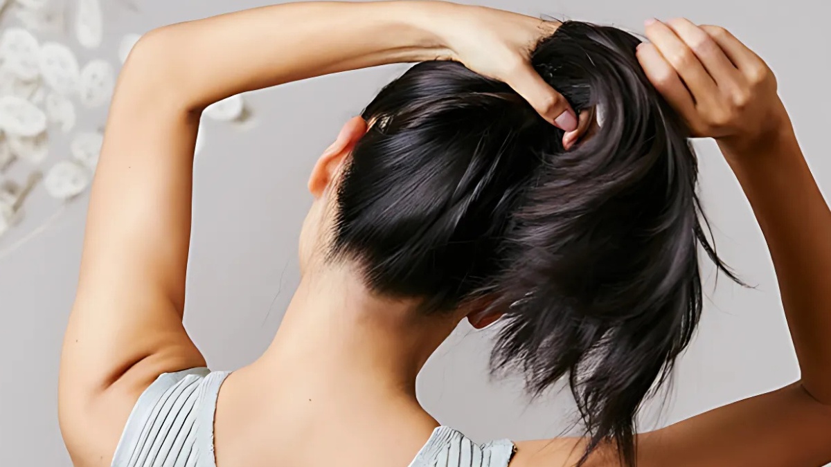 cach-lam-toc-het-bet-khong-can-goi-1 Người đang buộc tóc, quay lưng về phía máy ảnh, mặc áo màu xám nhạt, tóc đen dài.