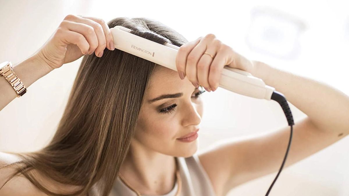 Người phụ nữ sử dụng máy ép tóc để làm thẳng tóc trong không gian sáng sủa.