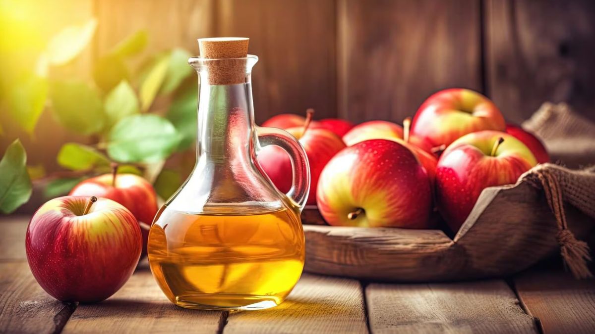Bình giấm táo và táo đỏ tươi trên bàn gỗ, ánh sáng tự nhiên chiếu sáng tạo không gian ấm cúng.