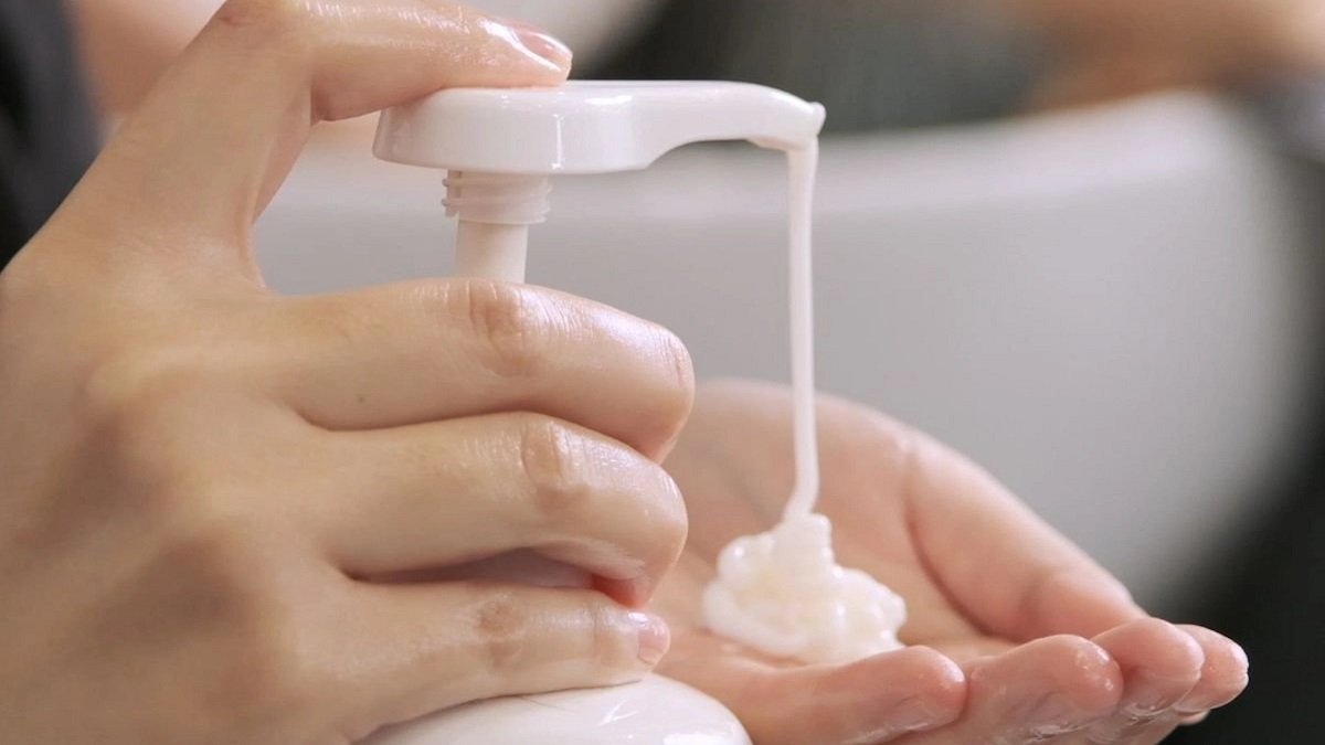 co-nen-goi-dau-truoc-khi-nhuom-toc-6 Tay người đang bơm kem dưỡng từ chai, kem chảy xuống lòng bàn tay.