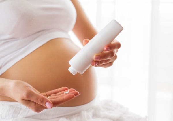 image10-16 Người đang đổ kem dưỡng từ chai trắng vào lòng bàn tay, phía trước là bụng bầu.