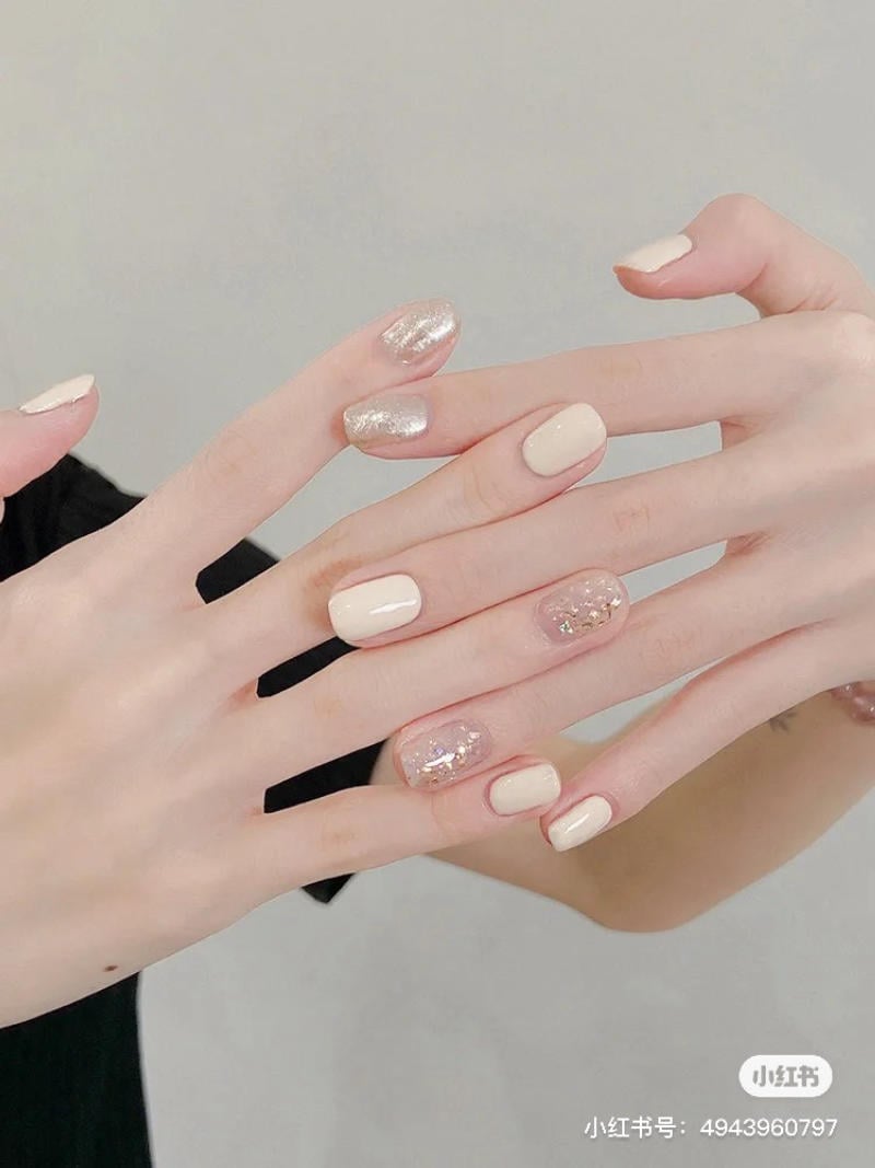 Bàn tay với móng tay được sơn màu be và đính kim tuyến lấp lánh.