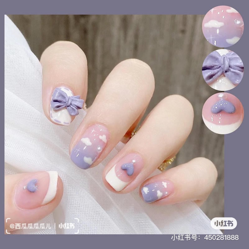 Móng tay được trang trí với họa tiết mây trắng và nơ tím trên nền hồng tím, kết hợp chi tiết trái tim và ngọc trai.