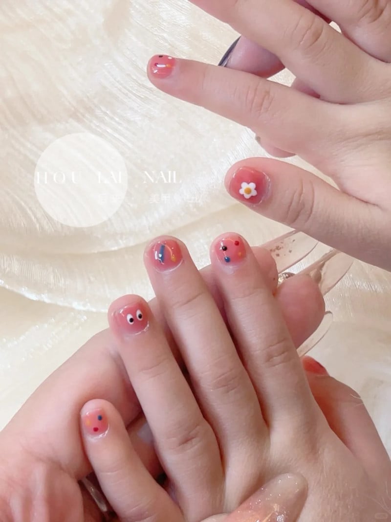 Bàn tay với móng tay được sơn màu sắc và trang trí hình hoa và khuôn mặt vui nhộn.