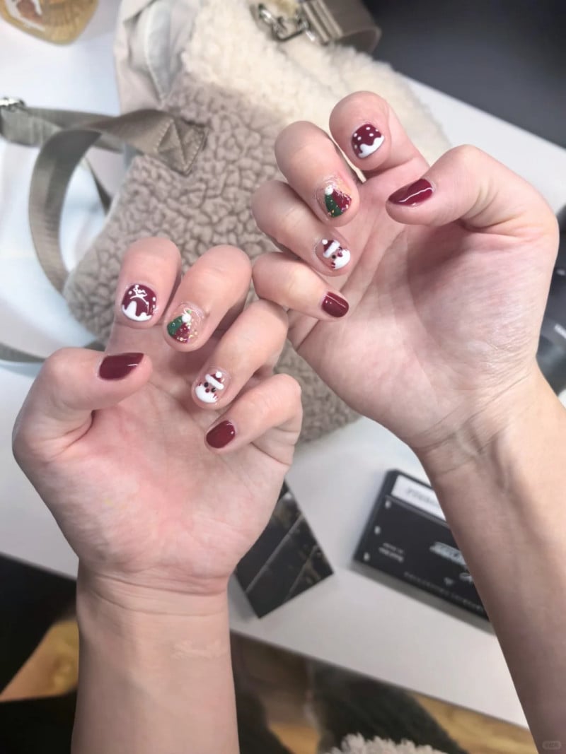 Hai bàn tay với móng tay được trang trí họa tiết Giáng Sinh, gồm cây thông và hình nón tuyết.