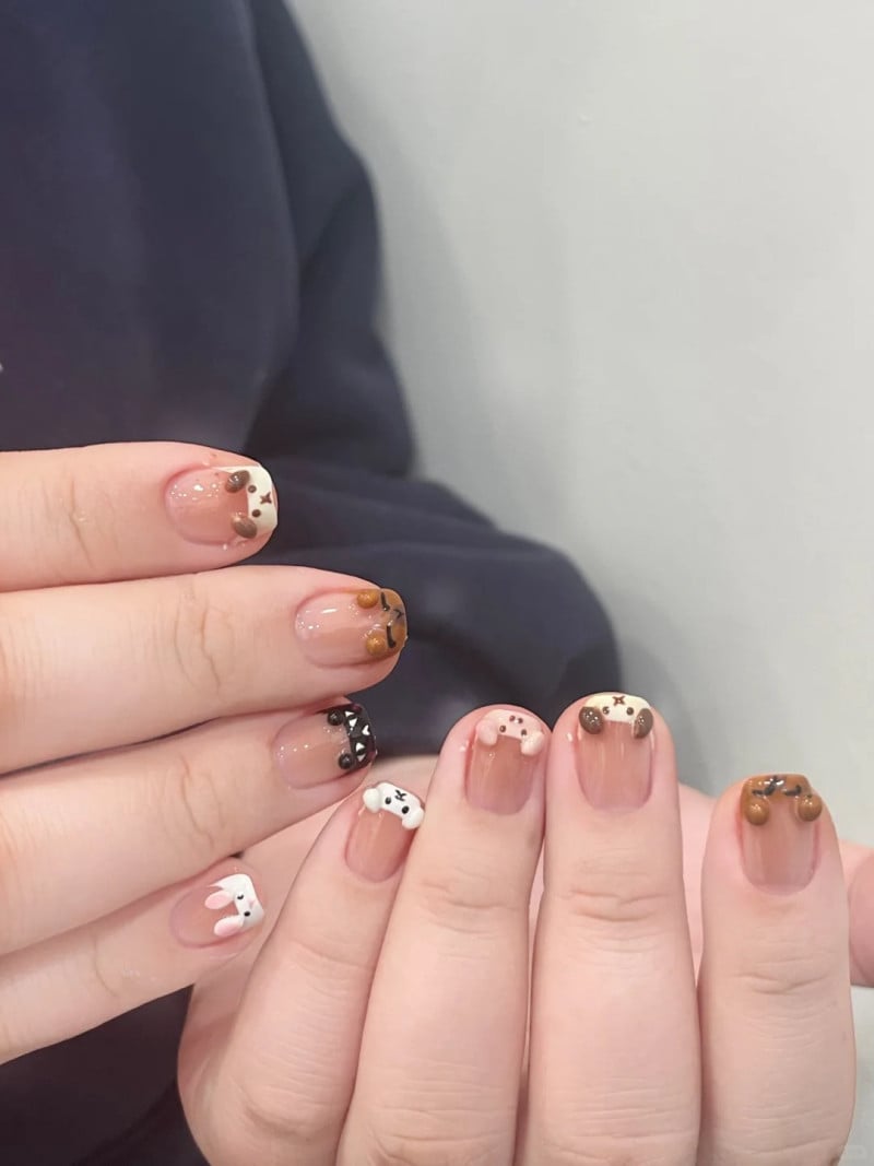 Bàn tay với móng tay được trang trí họa tiết động vật dễ thương nhiều màu sắc trên nền móng tự nhiên.